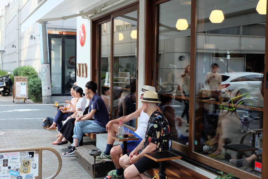 Customers sitting on benches outside cafe Fuglen Coffee Roasters Tokyo Japan