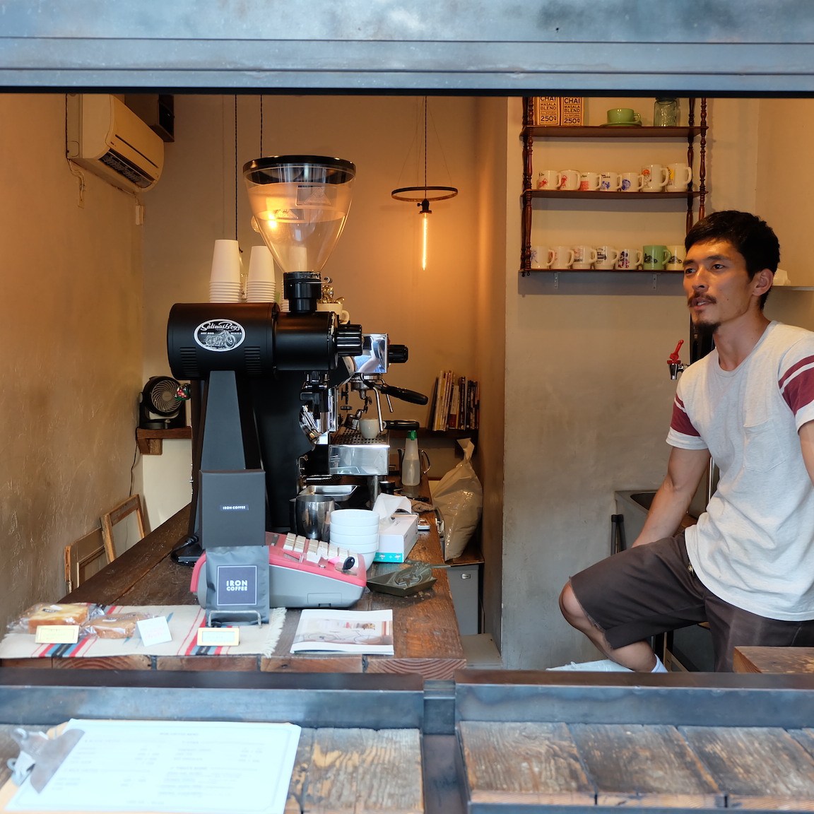 Barista sits on counter at Iron Coffee at Gotokuji Tokyo Japan